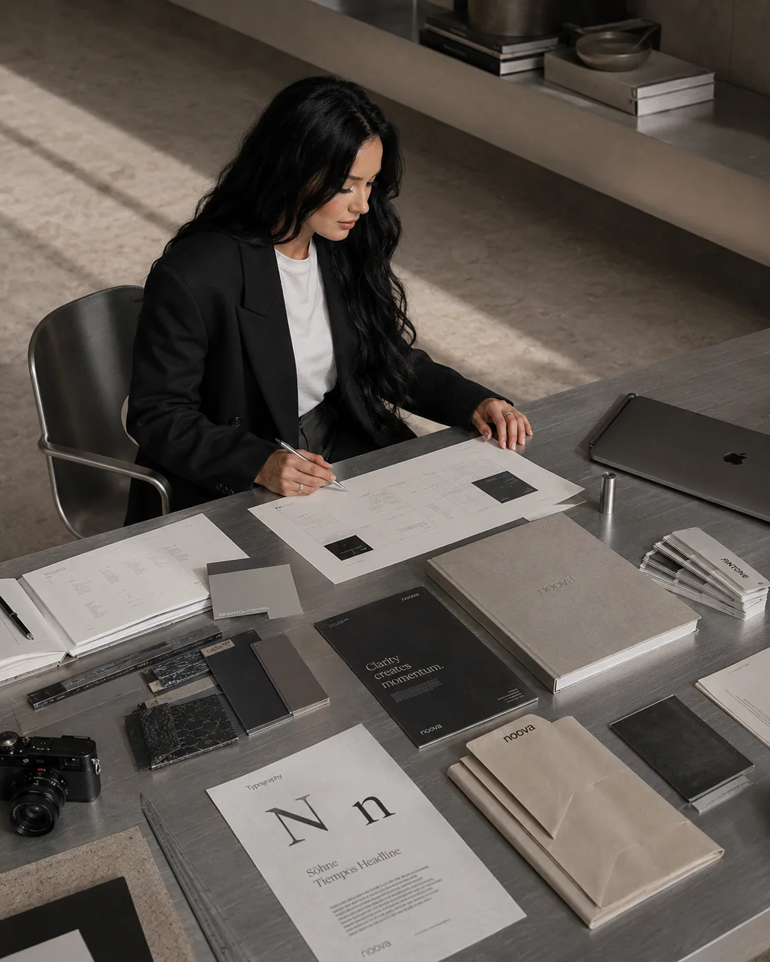The founder of noova at a brushed steel desk, reviewing brand systems and type specimens.