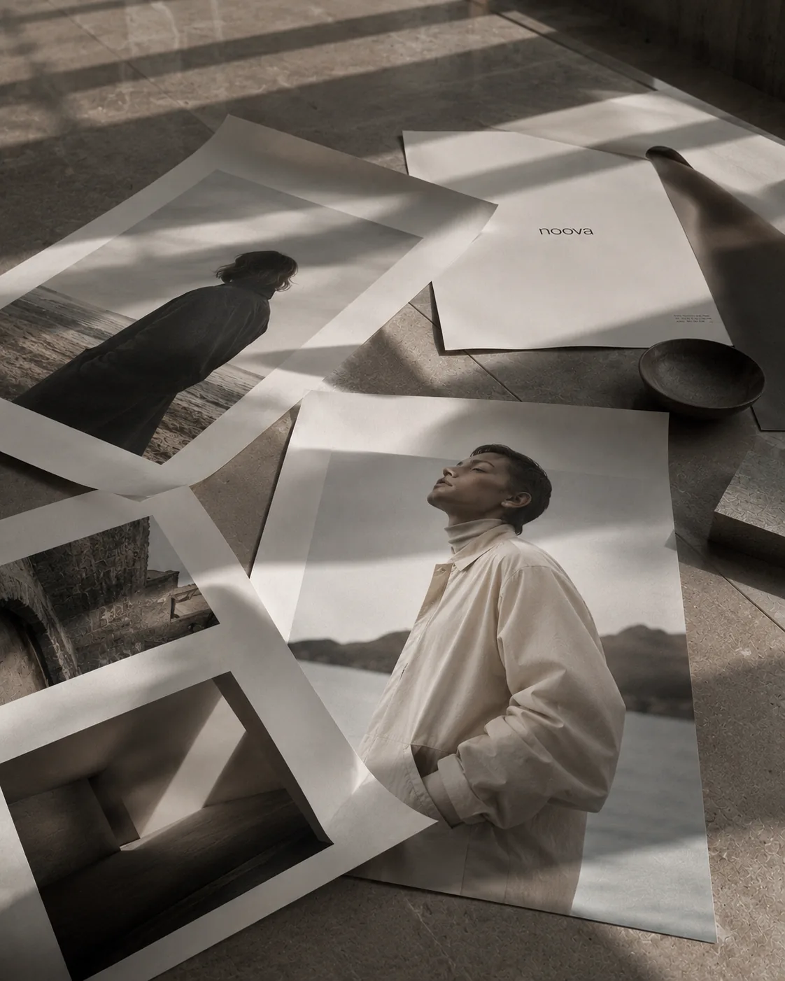 Editorial photography prints layered across a table in warm muted tones.